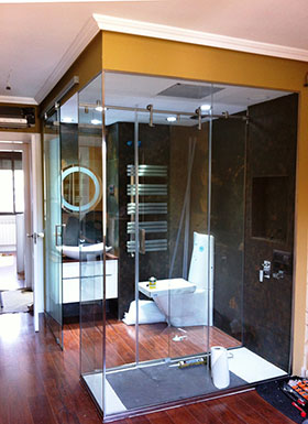 Ejemplo baño con ducha de acero y paredes de cristal